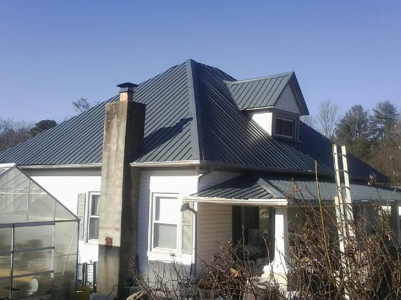 Dark blue standing seam metal roof on a white farmhouse with dormer — Slate & Tile Roof Repair by Roofing Brothers in Eastsound