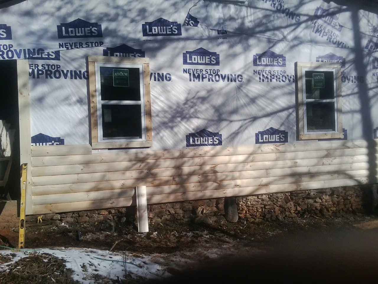 House wrap and new log siding going up on an exterior wall in Eastsound