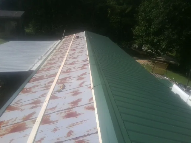 Old rusted panels beside newly installed green metal roofing — Wind Damage Roof Repair by Roofing Brothers in Eastsound