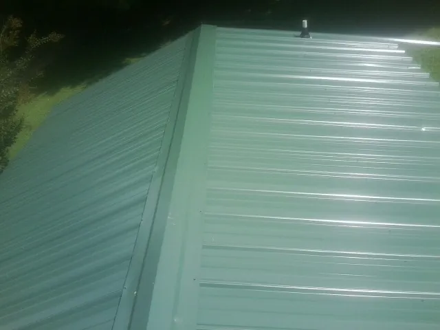 New green metal panels meeting at the ridge of a roof — Flat Roof Repair work by our crew in Eastsound