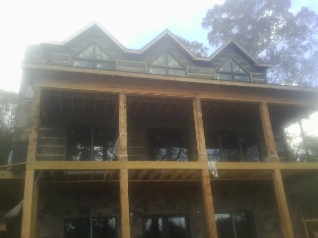 Dormers and porch framing on a large log home under construction — Roof Coating work by our crew in Eastsound