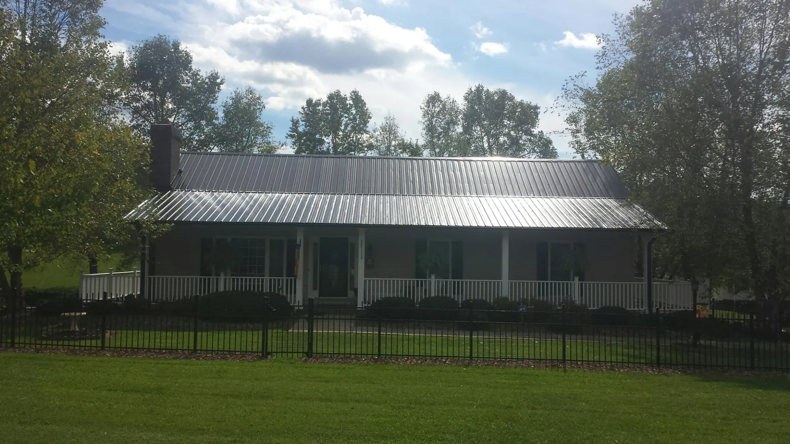 Gray metal roof on a brick ranch with a full width front porch — Gutter Guard Installation work by our crew in Eastsound