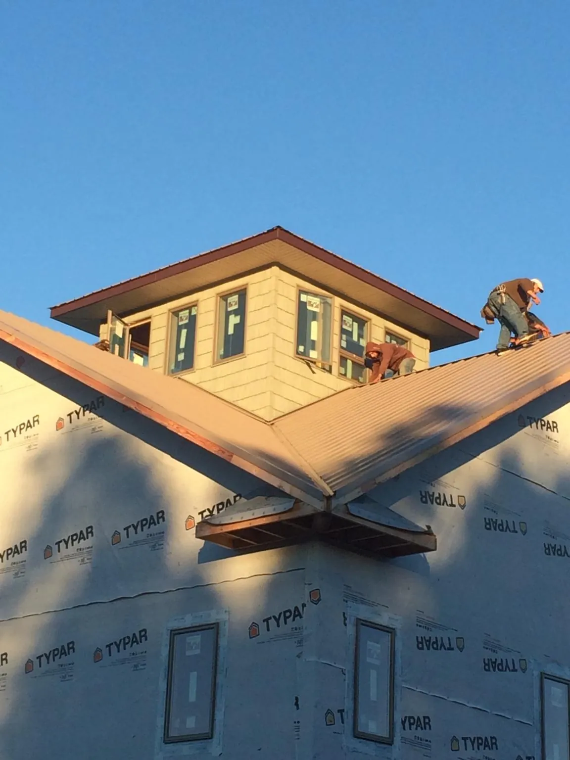 Roofers working around a rooftop cupola on a new metal roof at sunset — Roof Waterproofing in Eastsound by Roofing Brothers